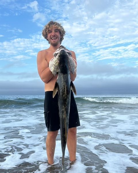 Dante G at the beach holding a fish he caught